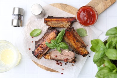Photo of Roasted beef ribs with spices, ketchup and drink on white tiled table, flat lay