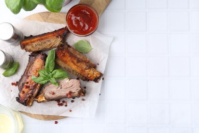 Photo of Roasted beef ribs with spices and ketchup on white tiled table, top view. Space for text