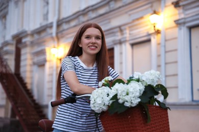 Photo of Beautiful teenage girl on bicycle with basket of flowers outdoors