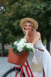 Photo of Beautiful woman near bicycle with basket of flowers on city street