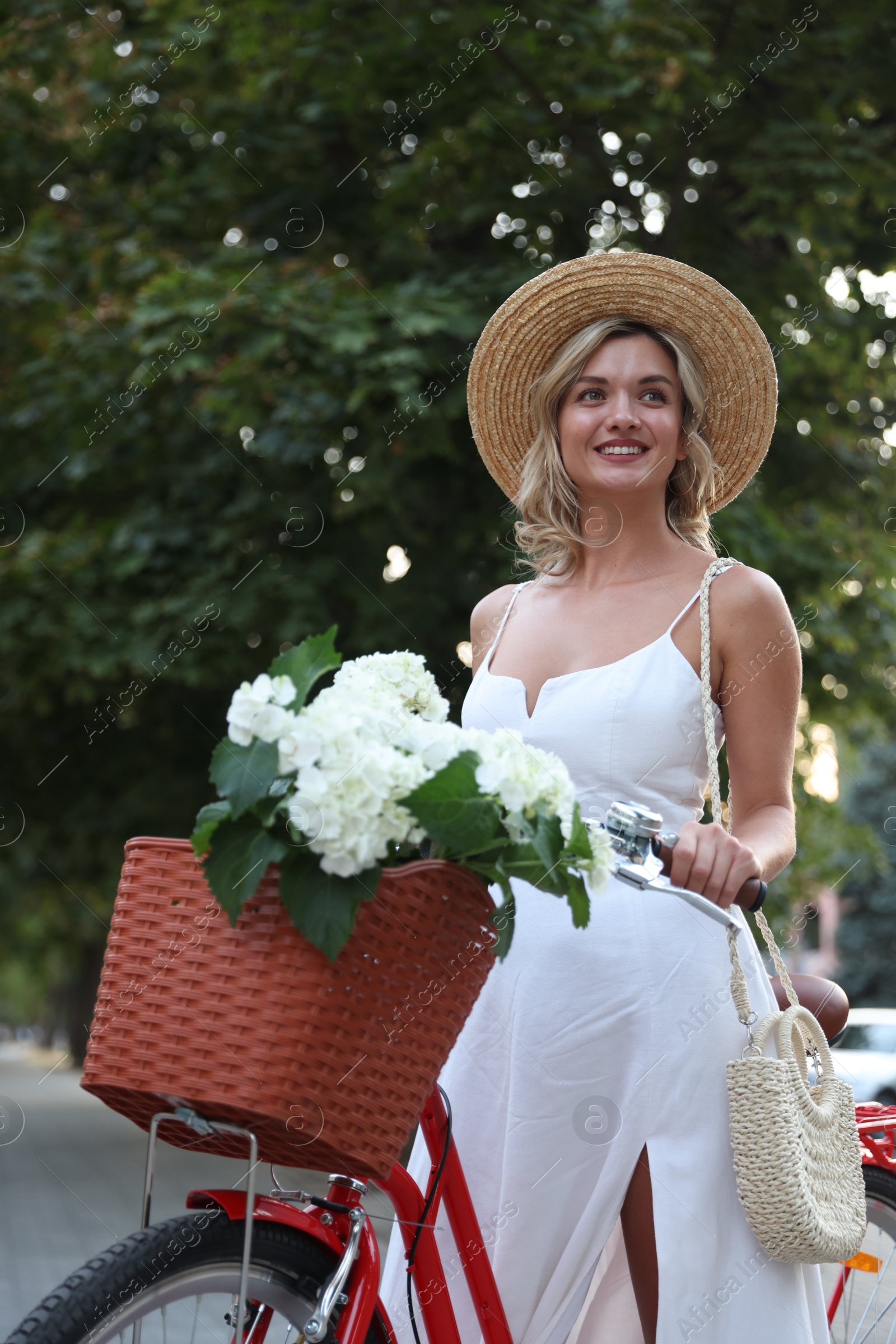 Photo of Beautiful woman near bicycle with basket of flowers on city street