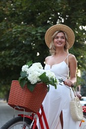 Photo of Beautiful woman near bicycle with basket of flowers on city street
