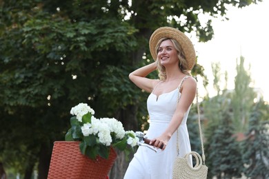 Photo of Beautiful woman on bicycle with basket of flowers outdoors