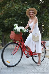 Photo of Beautiful woman on bicycle with basket of flowers outdoors