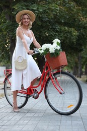 Photo of Beautiful woman on bicycle with basket of flowers outdoors