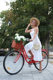 Photo of Beautiful woman on bicycle with basket of flowers outdoors