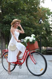 Photo of Beautiful woman on bicycle with basket of flowers outdoors