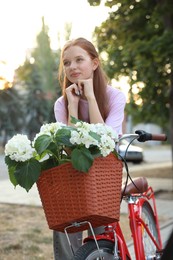 Photo of Beautiful teenage girl near bicycle with basket of flowers on city street