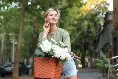 Photo of Beautiful woman on bicycle with basket of flowers on city street