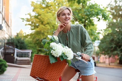 Photo of Beautiful woman on bicycle with basket of flowers on city street