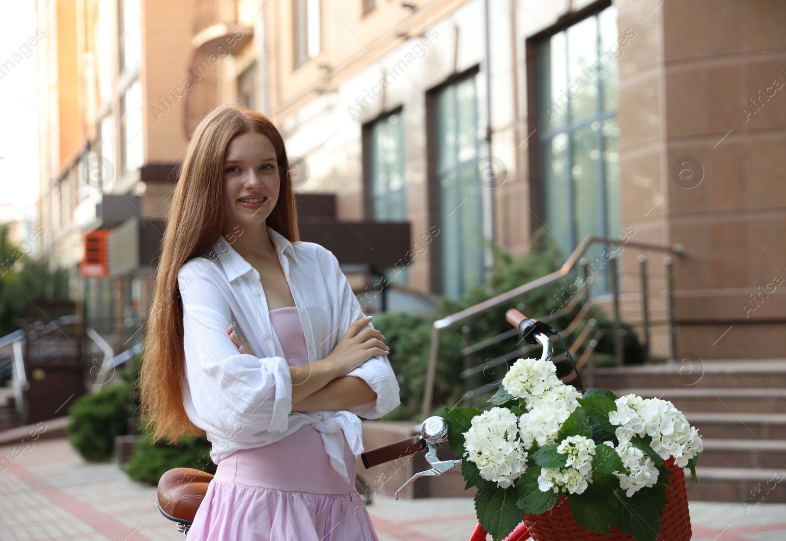Beautiful teenage girl near bicycle with basket of flowers on city street Photo of Beautiful teenage girl near bicycle with basket of flowers on city street