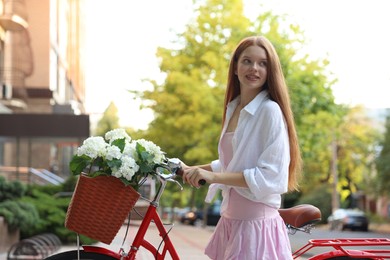 Photo of Beautiful teenage girl near bicycle with basket of flowers on city street