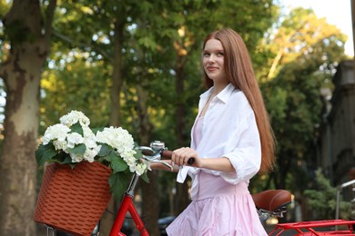 Photo of Beautiful teenage girl near bicycle with basket of flowers on city street