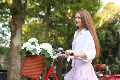 Photo of Beautiful teenage girl near bicycle with basket of flowers on city street