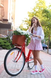 Photo of Beautiful teenage girl near bicycle with basket of flowers on city street