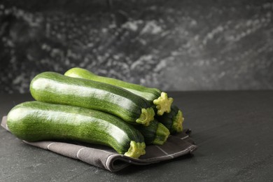 Photo of Fresh ripe zucchinis on black table, closeup. Space for text