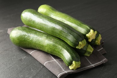 Photo of Fresh ripe zucchinis on black table, closeup