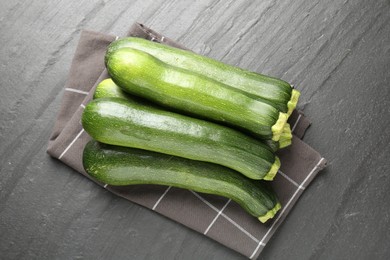 Photo of Fresh ripe zucchinis on black table, top view