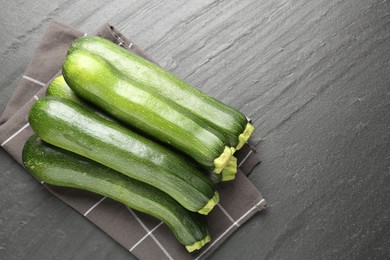 Photo of Fresh ripe zucchinis on black table, top view. Space for text