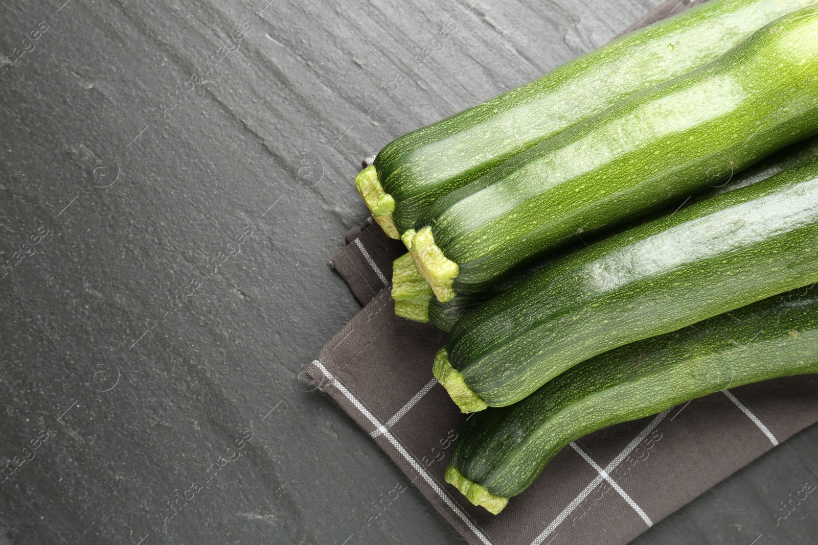 Fresh ripe zucchinis on black table, top view. Space for text Photo of Fresh ripe zucchinis on black table, top view. Space for text
