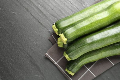 Photo of Fresh ripe zucchinis on black table, top view. Space for text