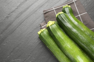 Photo of Fresh ripe zucchinis on black table, top view. Space for text