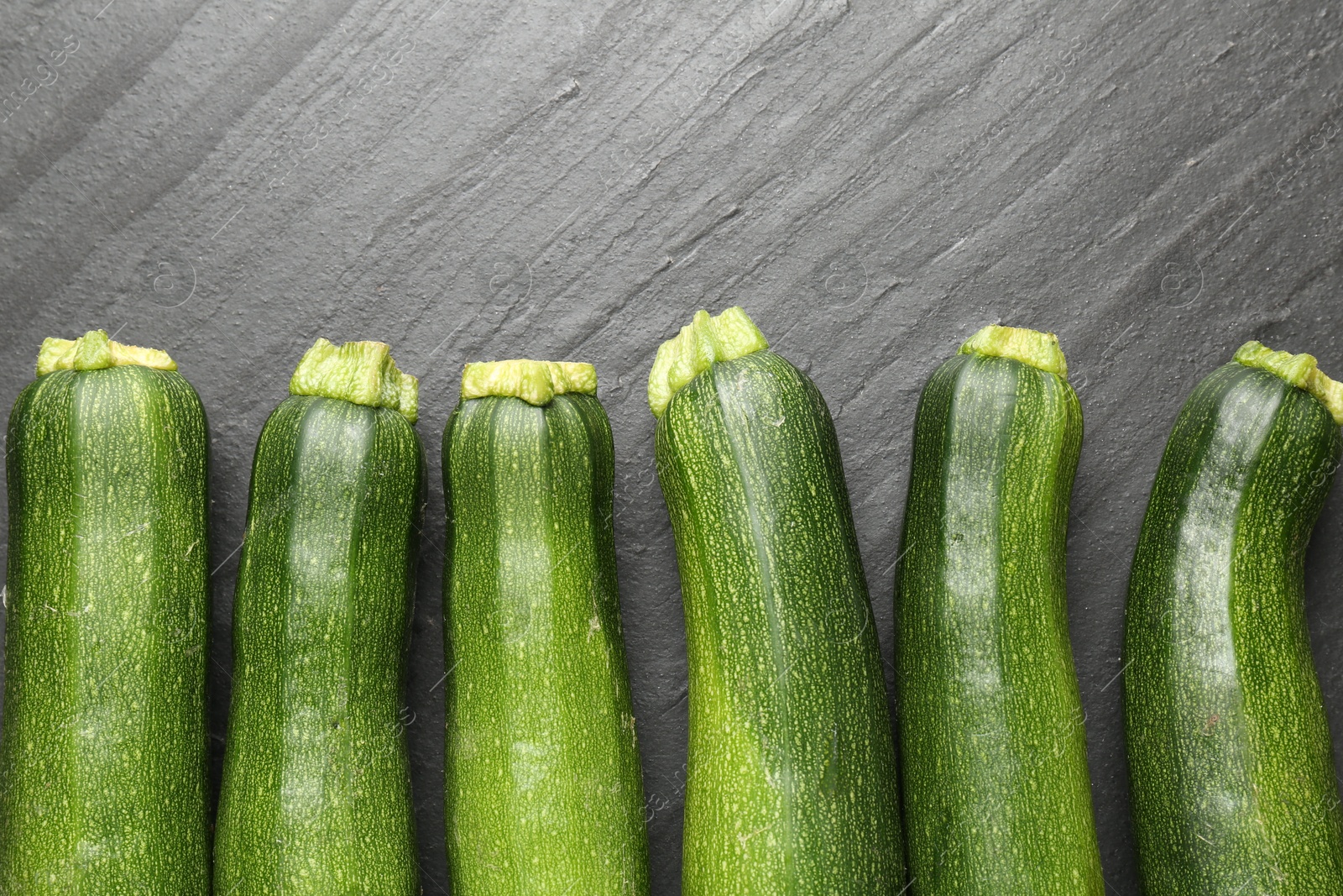 Fresh ripe zucchinis on black table, flat lay Photo of Fresh ripe zucchinis on black table, flat lay