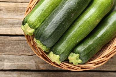 Photo of Fresh ripe zucchinis in wicker basket on wooden table, top view