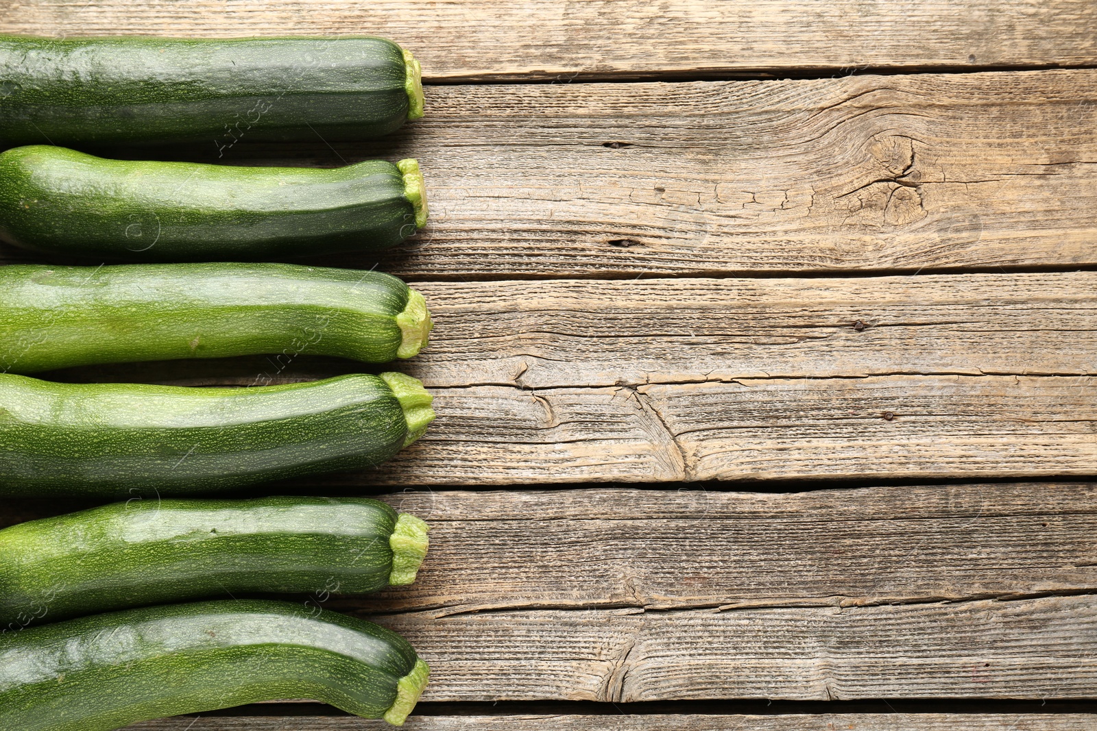 Fresh ripe zucchinis on wooden table, flat lay. Space for text Photo of Fresh ripe zucchinis on wooden table, flat lay. Space for text