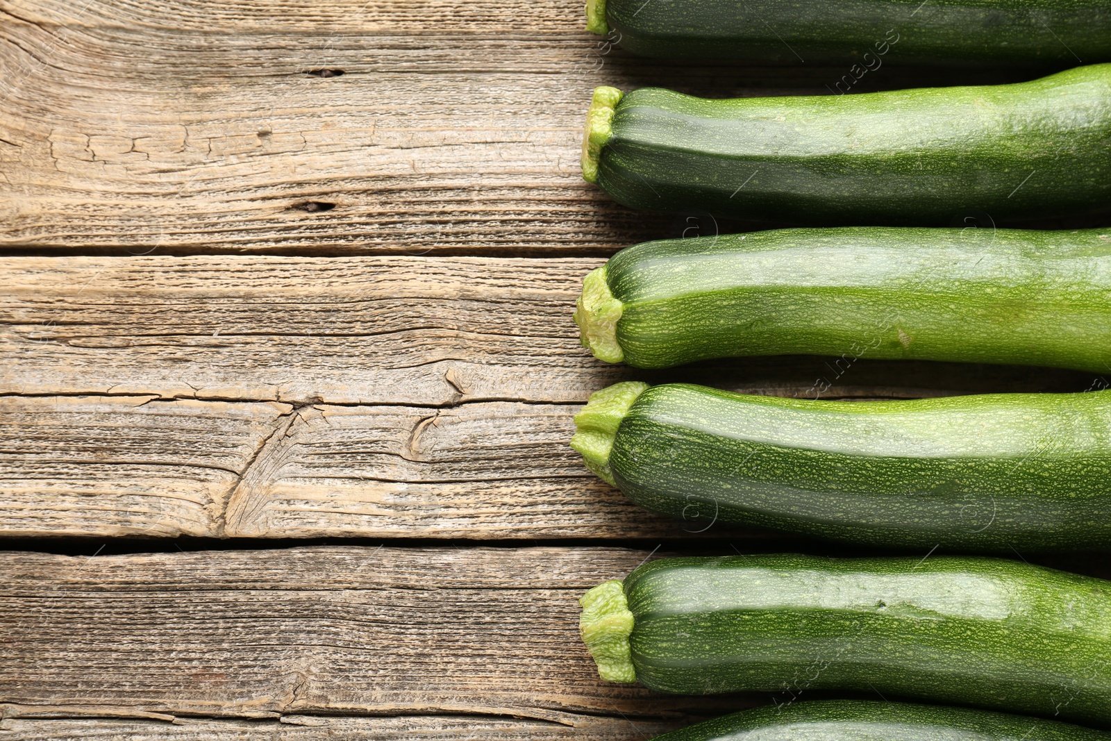 Fresh ripe zucchinis on wooden table, flat lay. Space for text Photo of Fresh ripe zucchinis on wooden table, flat lay. Space for text