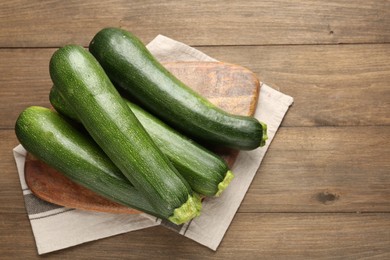 Photo of Fresh ripe zucchinis on wooden table, top view. Space for text