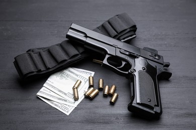 Photo of Gun, cartridges and dollar banknotes on black background