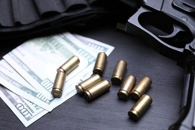 Photo of Gun, cartridges and dollar banknotes on black background, closeup