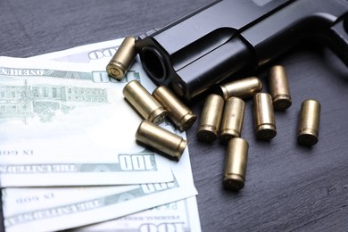 Photo of Gun, cartridges and dollar banknotes on black background, closeup