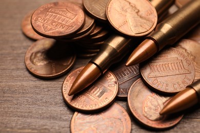 Photo of Firearm cartridges and coins on wooden table, closeup