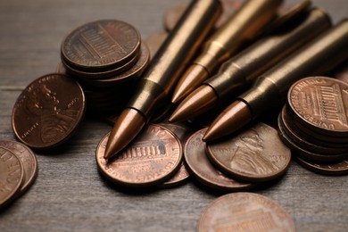 Photo of Firearm cartridges and coins on wooden table, closeup