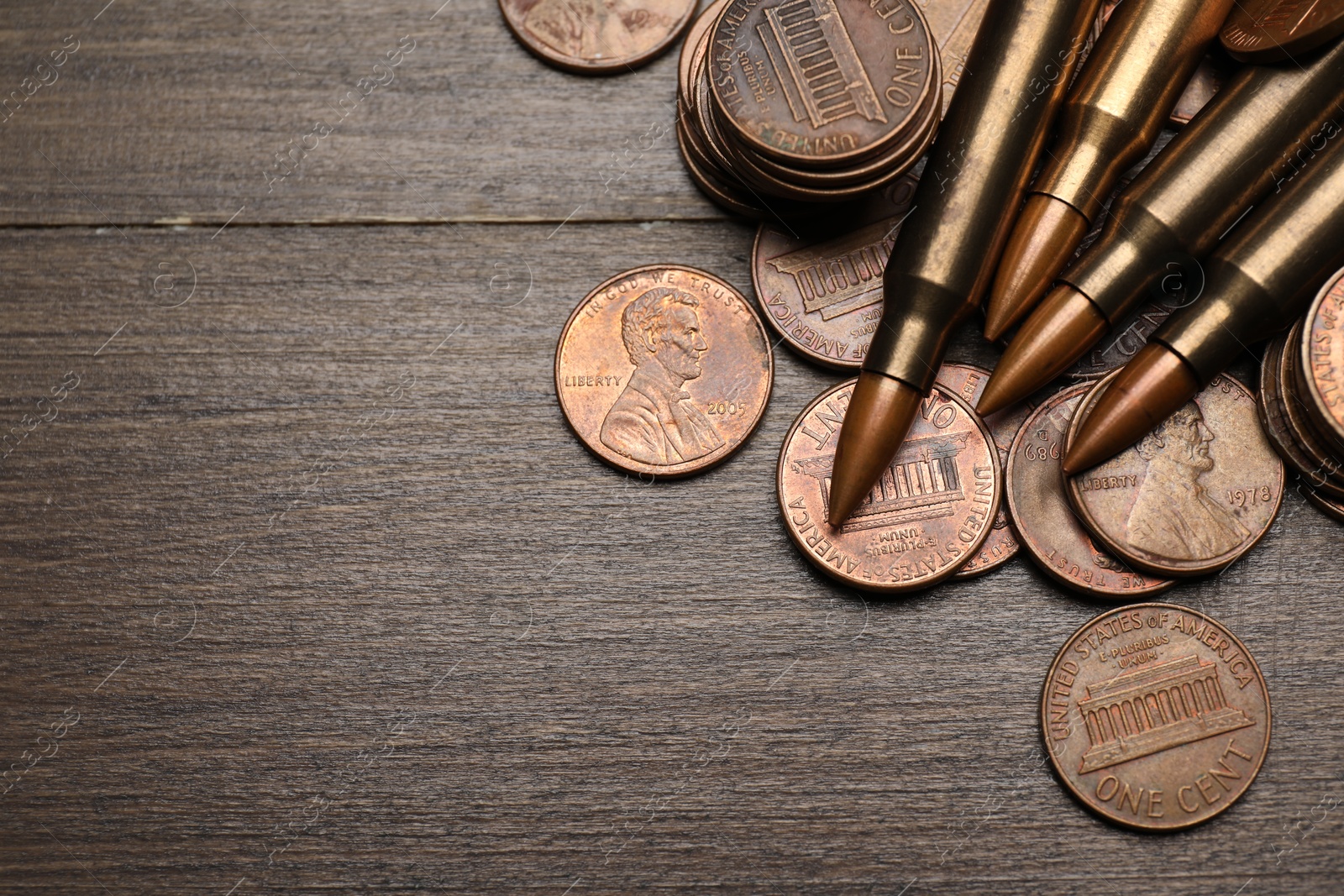 Firearm cartridges and coins on wooden table, flat lay. Space for text Photo of Firearm cartridges and coins on wooden table, flat lay. Space for text