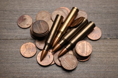 Photo of Firearm cartridges and coins on wooden table, flat lay