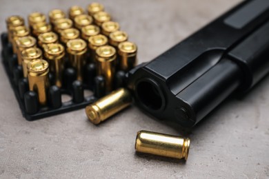 Photo of Gun and cartridges on grey background, closeup