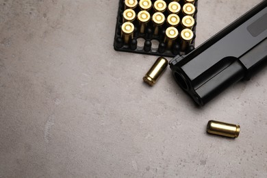 Photo of Gun and cartridges on grey background, flat lay. Space for text