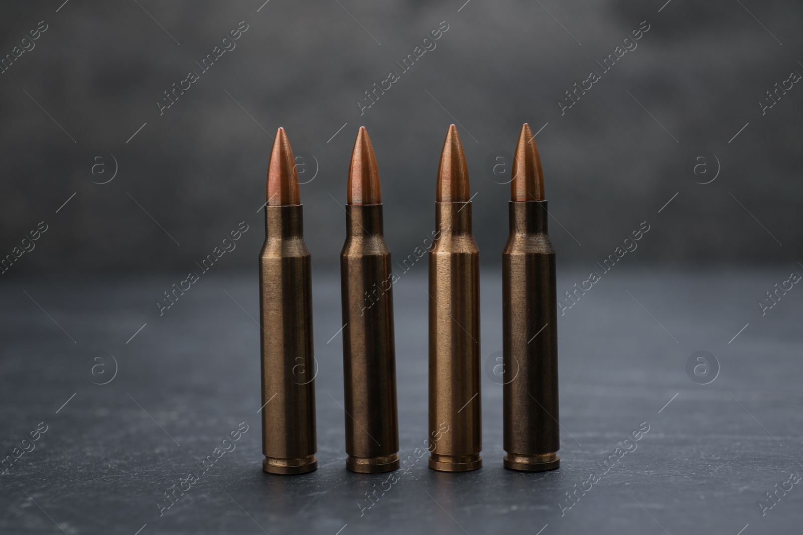 Firearm cartridges on grey table against smoke, closeup Photo of Firearm cartridges on grey table against smoke, closeup