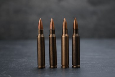 Photo of Firearm cartridges on grey table against smoke, closeup