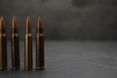 Photo of Firearm cartridges on grey table against smoke, closeup. Space for text