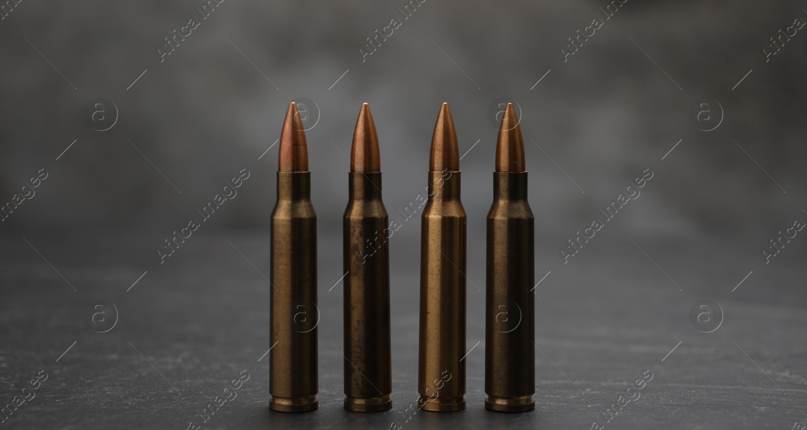 Firearm cartridges on grey table against smoke, closeup Photo of Firearm cartridges on grey table against smoke, closeup