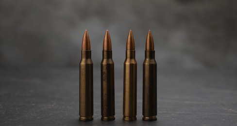 Photo of Firearm cartridges on grey table against smoke, closeup