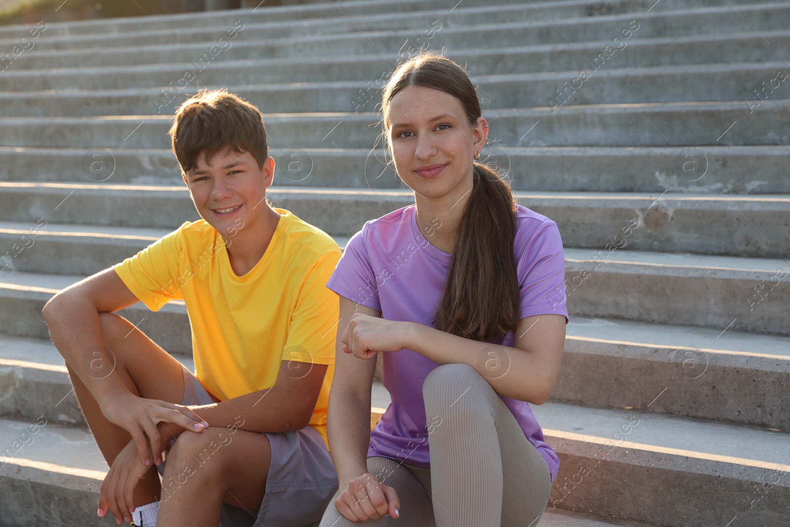 Teenage girl and boy sitting on stairs outdoors after training Photo of Teenage girl and boy sitting on stairs outdoors after training