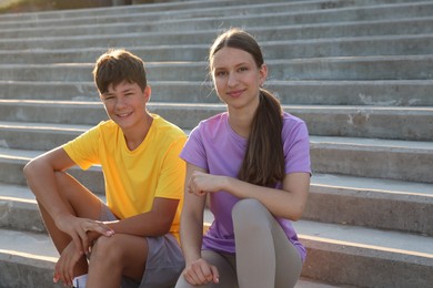 Photo of Teenage girl and boy sitting on stairs outdoors after training