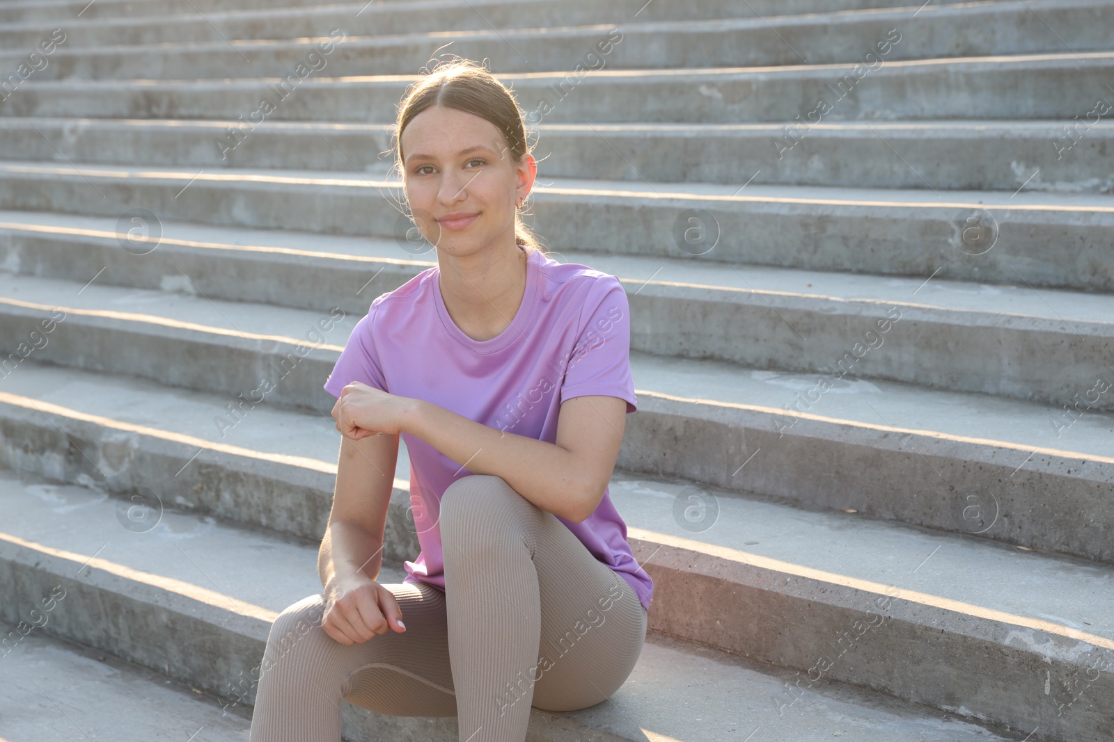 Teenage girl sitting on stairs outdoors after training. Space for text Photo of Teenage girl sitting on stairs outdoors after training. Space for text