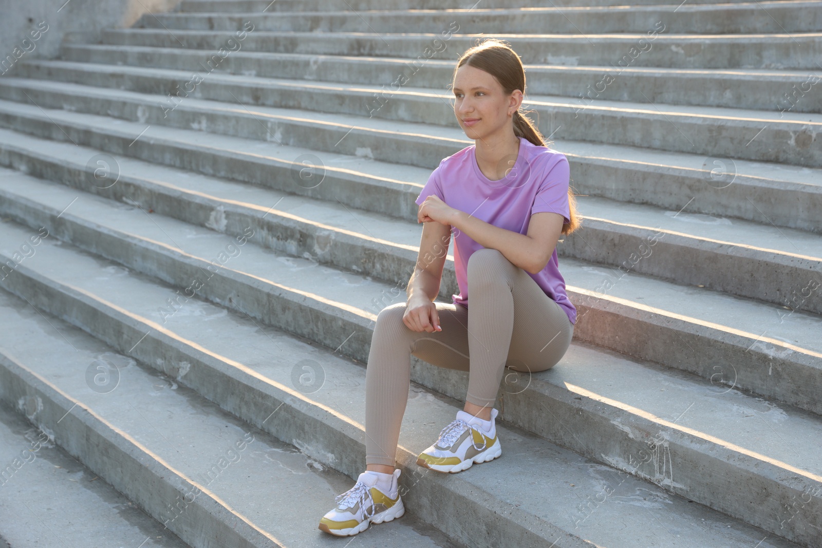 Teenage girl sitting on stairs outdoors after training. Space for text Photo of Teenage girl sitting on stairs outdoors after training. Space for text