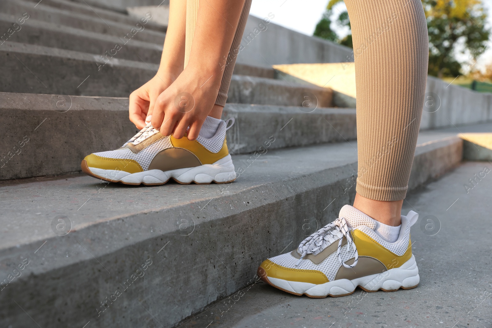 Teenage girl tying shoelaces before running on stairs outdoors, closeup Photo of Teenage girl tying shoelaces before running on stairs outdoors, closeup